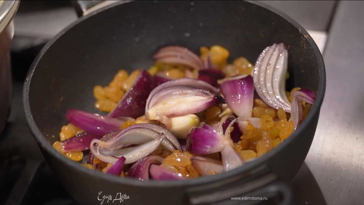 Обжаренные ножки переложить на тарелку, а в сотейник выложить лук, чеснок, все посолить и перемешать, затем добавить изюм, еще раз перемешать и слегка обжарить.