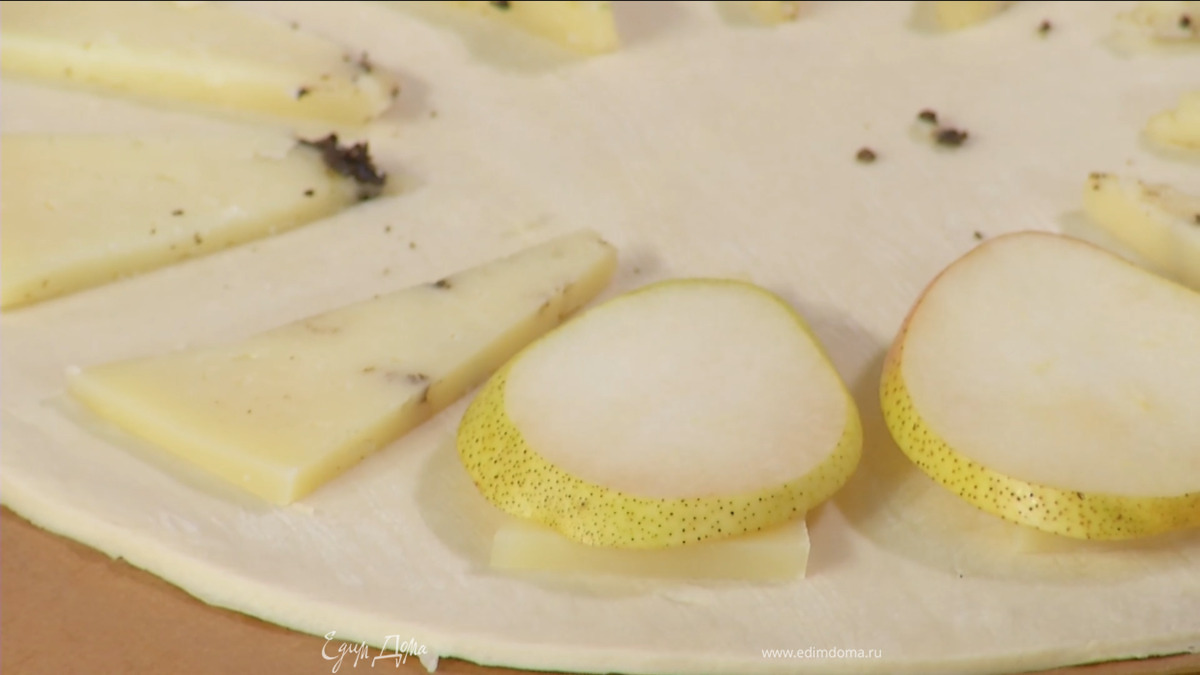 Сыр нарезать треугольниками и выложить на тесто, на каждый кусочек сыра поместить ломтик груши.