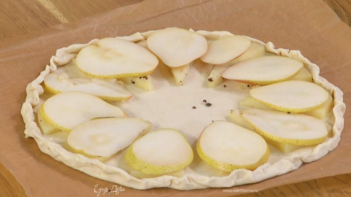 Присобрать тесто по краям, чтобы получился бортик, и смазать не закрытую сыром с грушами поверхность желтком, смешанным с солью.