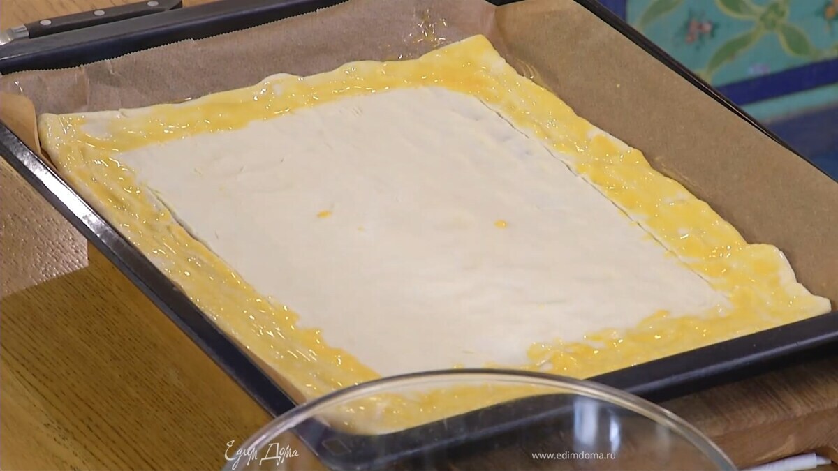 Яйцо размешать с оставшимися сливками и щепоткой соли, смазать бортики у теста.