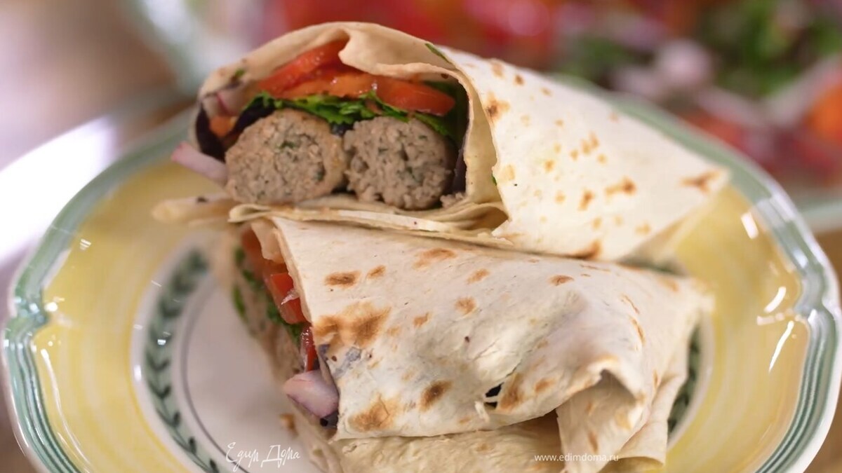 Лаваш разрезать пополам, на каждую часть выложить оставшуюся кинзу с фиолетовым базиликом, листья петрушки, две колбаски и помидоры с луком, затем свернуть конвертиком.