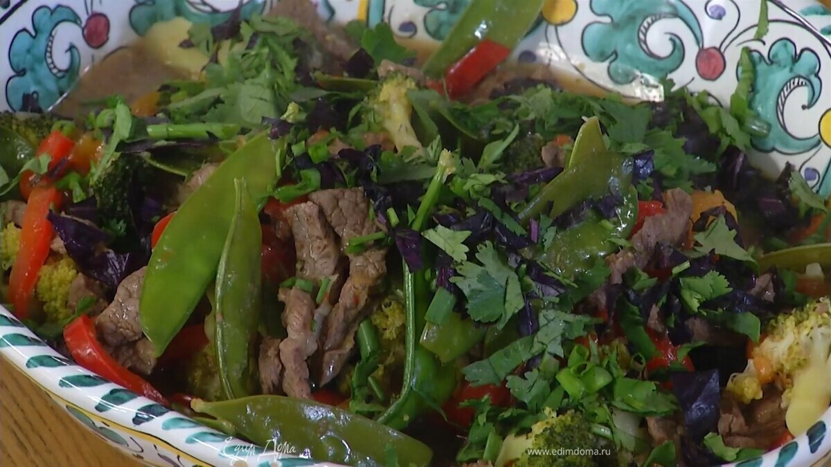 Мясо с овощами переложить в блюдо, посыпать измельченной зеленью и кунжутом.