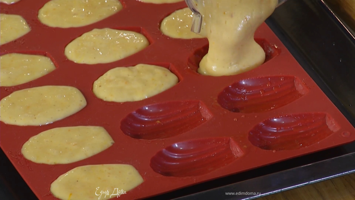 Смазать формы для печенья мадлен оставшимся сливочным маслом и разложить тесто.