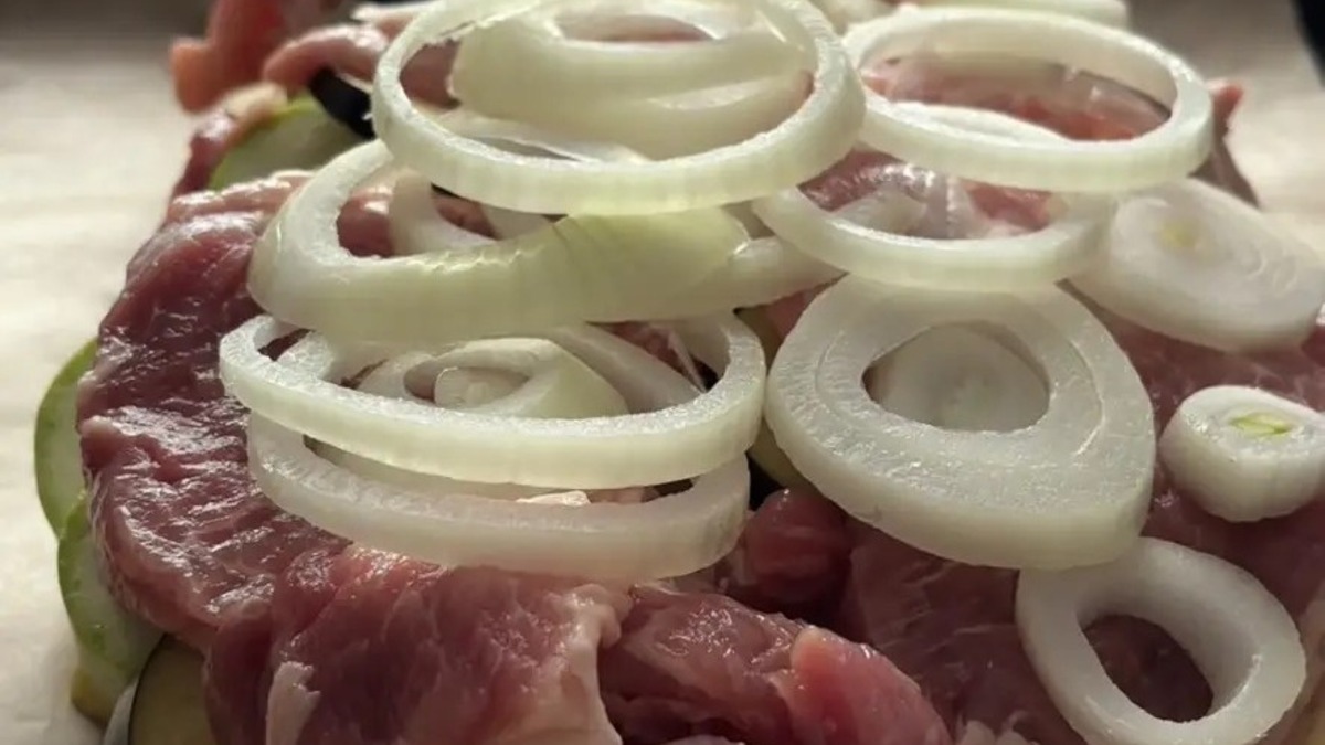 Очистите лук, нарежте на кольца, выложите на мясо.