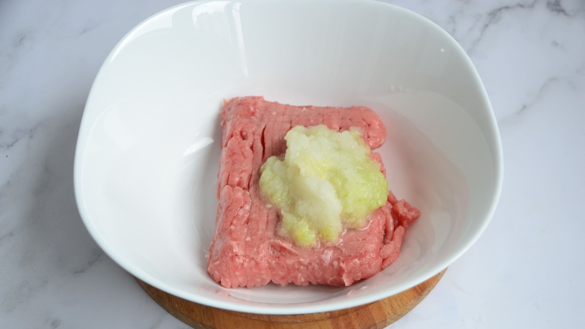 Добавьте лук к фаршу, посолите и поперчите по вкусу, смешайте в однородную массу.