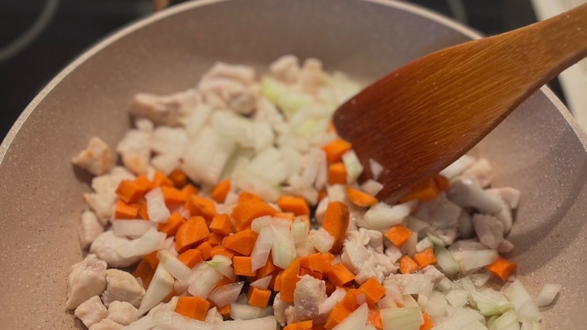 К курице добавьте морковь и лук, нарезанные кубиком. Обжаривайте еще 5–7 минут до мягкости овощей.