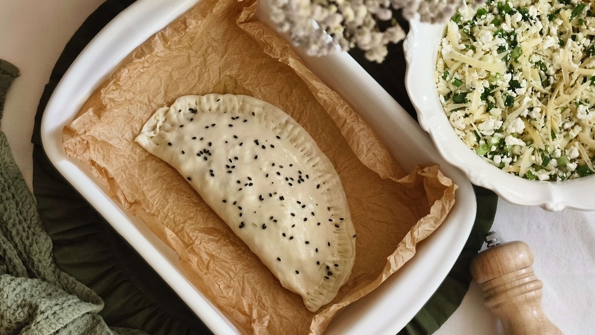 Смажьте пирожок оливковым маслом, посыпьте кунжутом. Выпекайте в разогретой до 180℃ духовке в течение 7-10 минут.