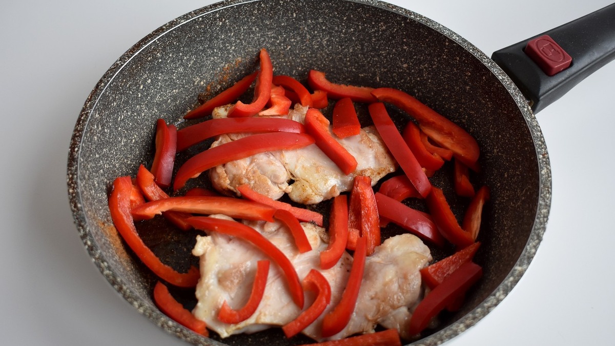 Переворачиваю кусочки филе, добавляю сладкий перец нарезанный соломкой.