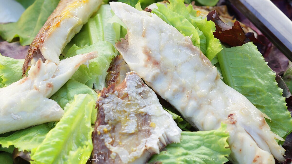Копченая рыба на листьях салата